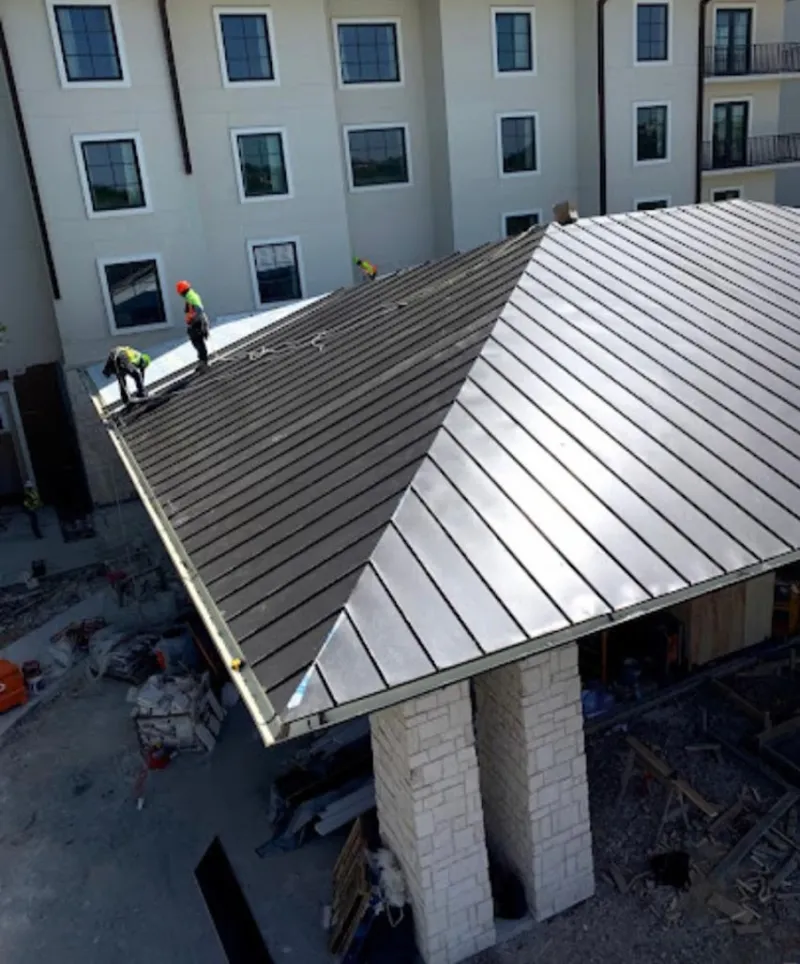 Crew installing standing seam metal roof panels on a commercial project in Barling